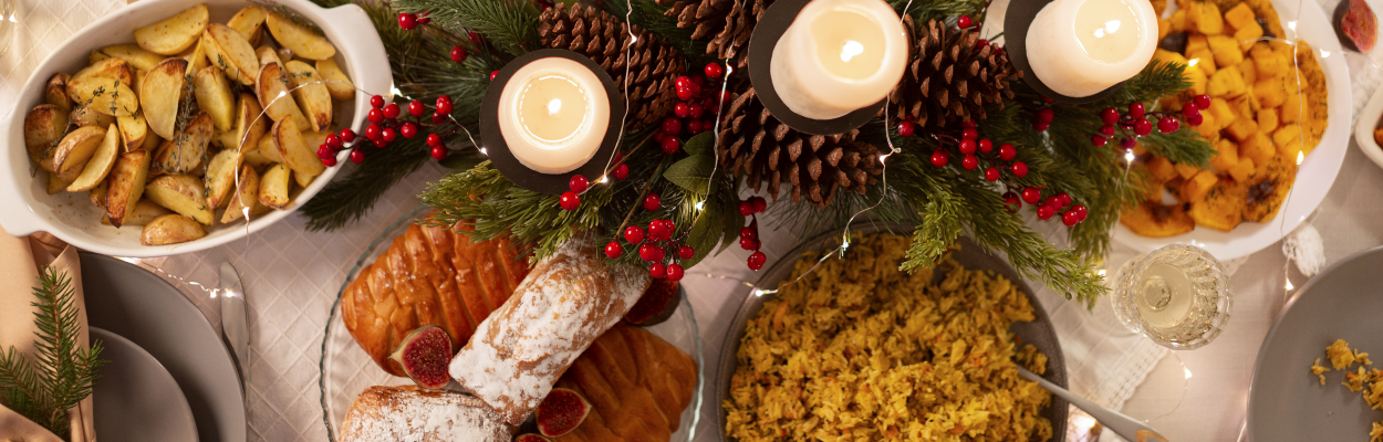 Em uma grande mesa, vemos vários pratos típicos de Natal espalhados representando uma ceia de Natal para diabéticos.
