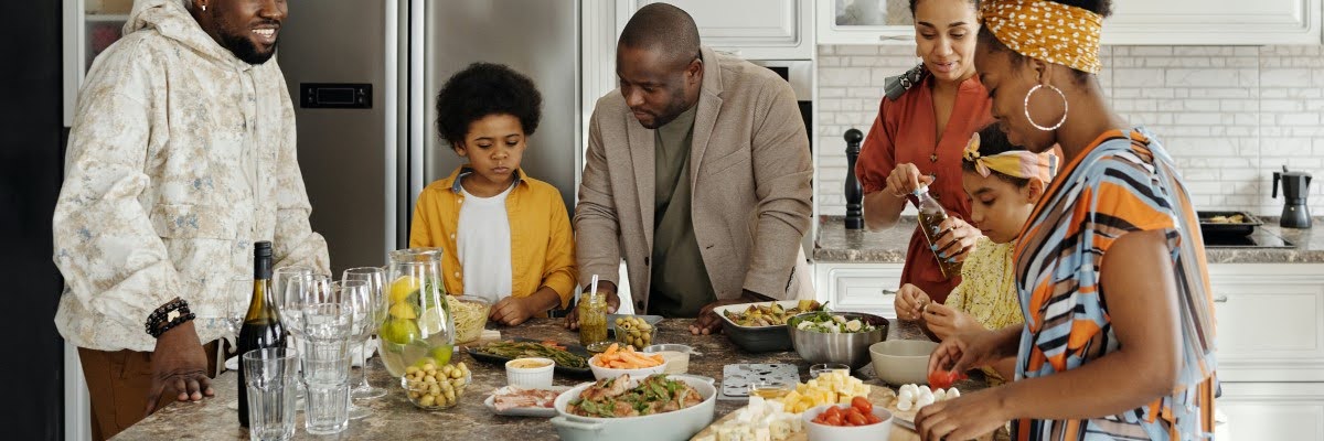 Uma família negra se reúne na cozinha para uma refeição para representar a sustentabilidade alimentar.