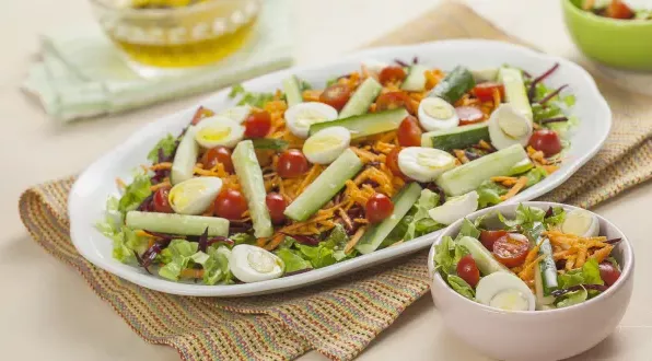 Salada refrescante e colorida em uma travessa branca. Ao lado, temos uma tigela menor com uma porção de salada.