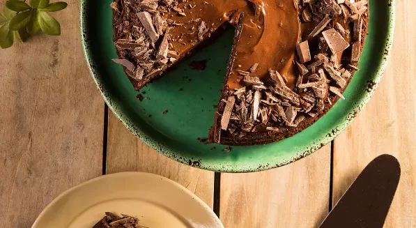 Bolo de chocolate cortado em cima de um prato verde.