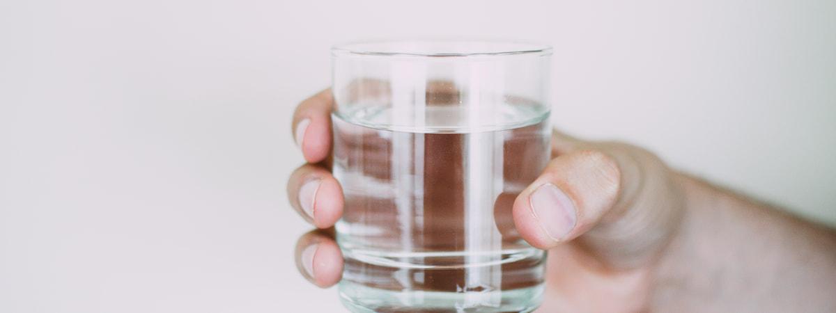 Homem segurando um copo de vidro com água