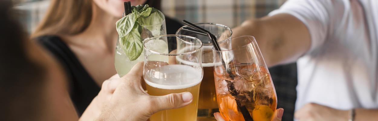 Grupo de amigos brindando copos e taças com diversas bebidas. A imagem representa quanto tempo o álcool fica no corpo. 